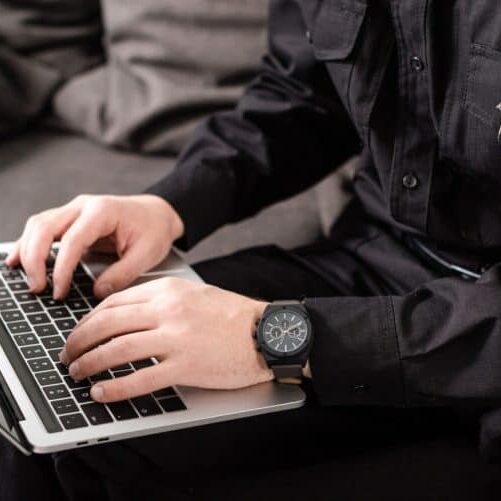 cropped view of policeman typing on laptop keyboard